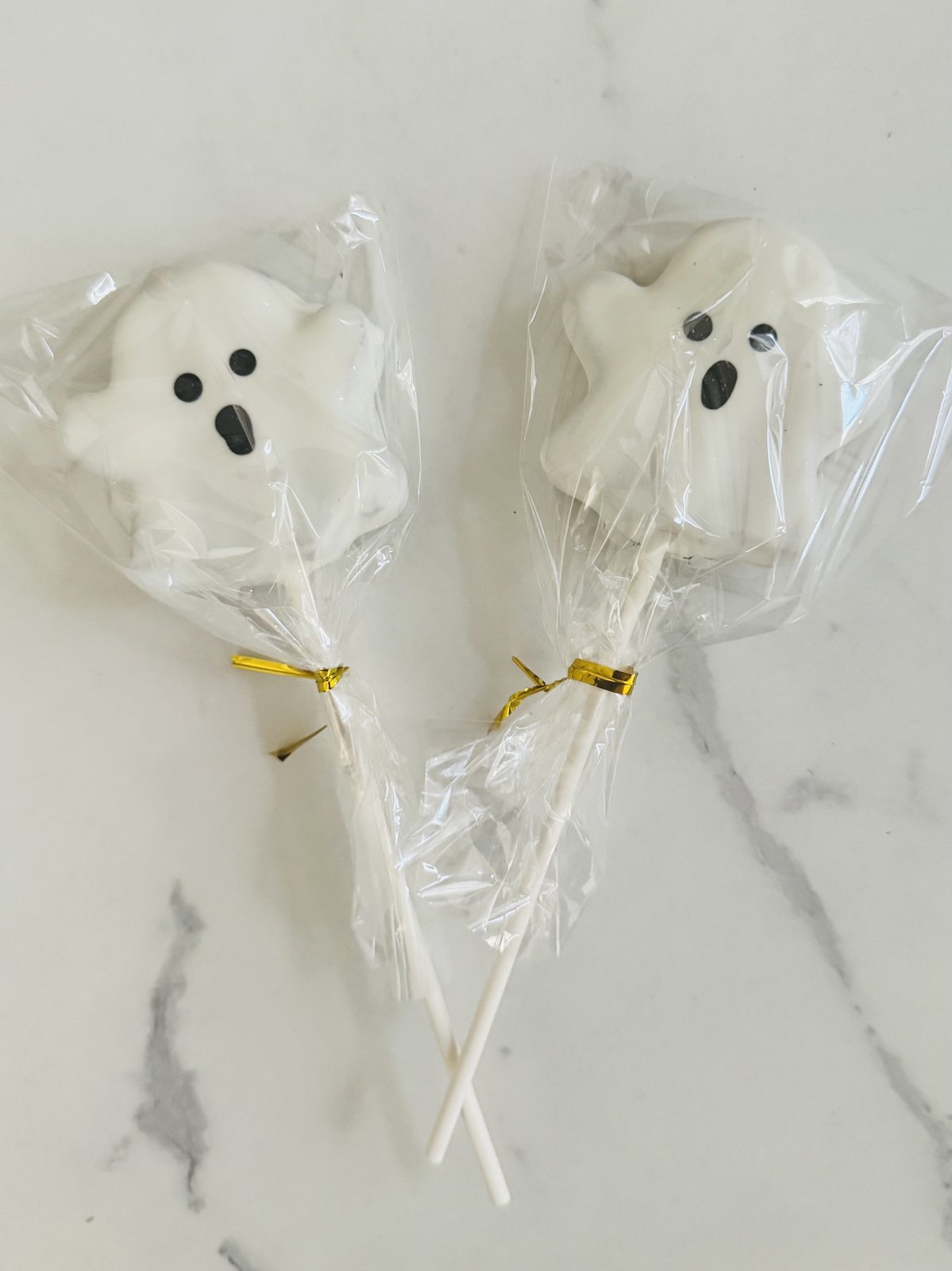 Two white ghost cake pops on marble